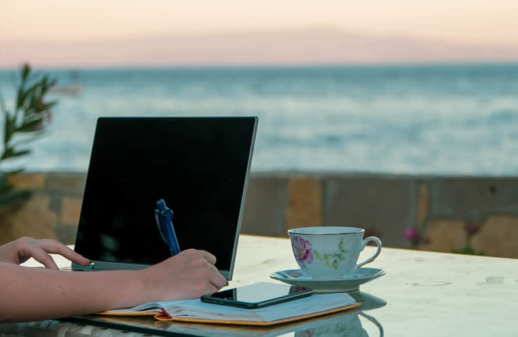 Woman working home writing and taking notes at the beach. Photo by fulltimetraveller via iStock by Getty Images