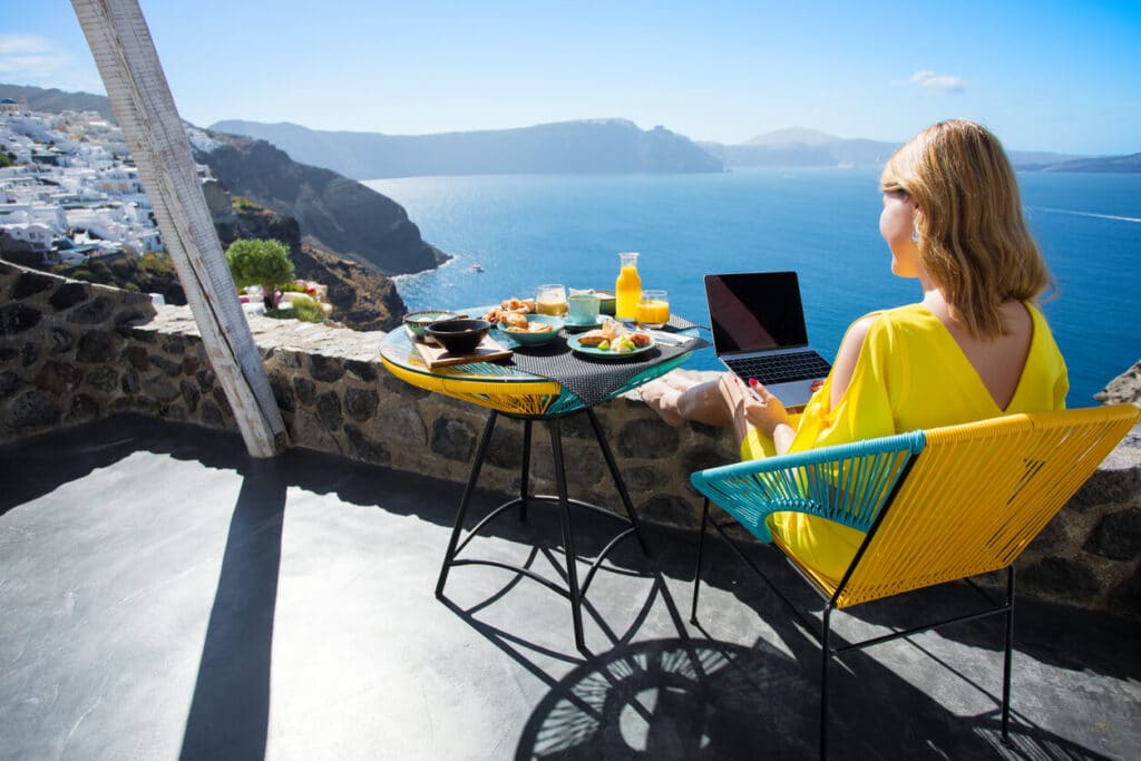 Woman working with laptop while on vacation in Mediterranean. Photo by grinvalds via iStock by Getty Images
